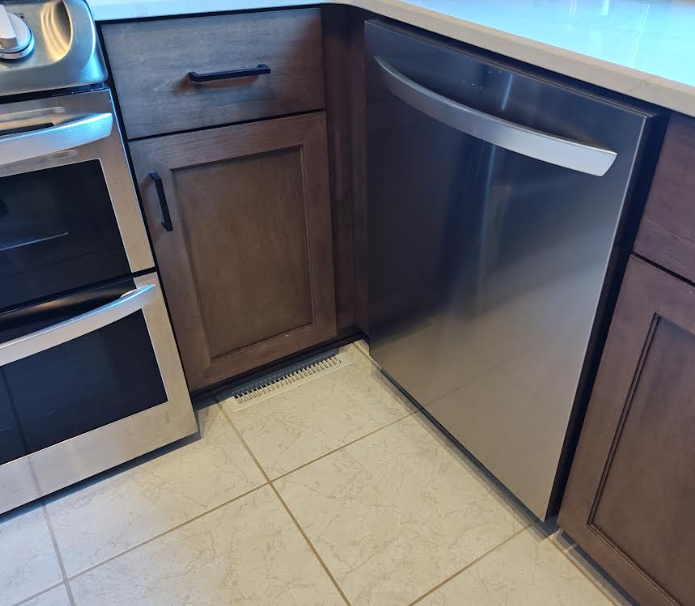 Modern stainless steel dishwasher installed between kitchen cabinets, shown for GFCI code compliance per 2023 NEC 210.8(D).