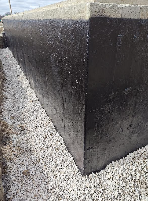 Damp proofed foundation wall showing correct gravel placement for perimeter drain system, highlighting field-ready installation before inspection.