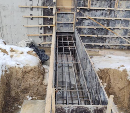 Concrete foundation wall in Zone 5 protected during winter construction, insulated blankets visible on jobsite
