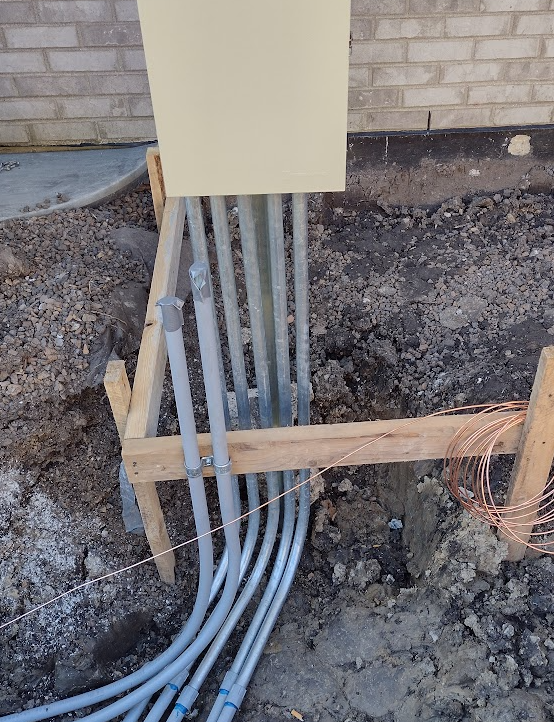 Pool subpanel installation with multiple underground conduits entering at the base, showing code-compliant separation and preparation for wiring at a residential pool equipment location.