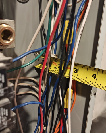 Wire nuts in service panel wiring gutter with conductors measured for NEC 312.8 fill limits.