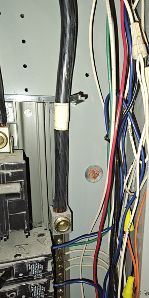 Interior of residential service panel showing conductors and wire-nut splices used to illustrate NEC 312.8 gutter fill rules and cross-section limits.