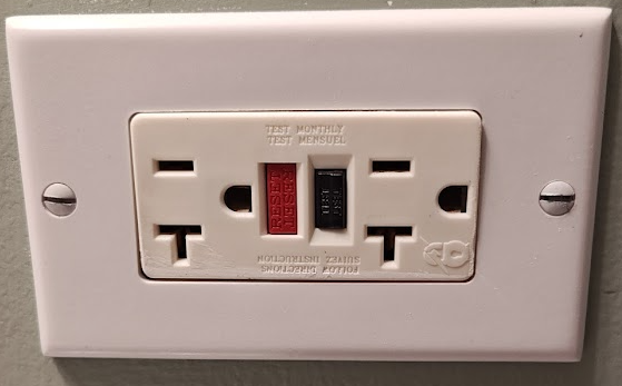 Close-up of a GFCI outlet showing test and reset buttons for NEC code compliance