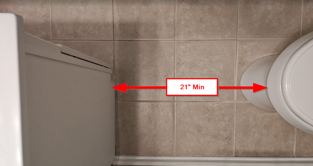 Overhead view of toilet and vanity with red arrow showing 21 inch minimum front clearance per IRC bathroom code