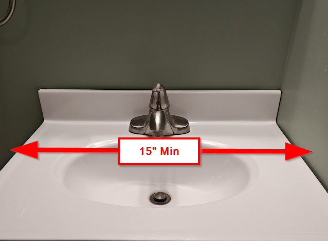 Bathroom sink with red arrow showing 15 inch minimum side clearance from centerline to wall as required for lavatories