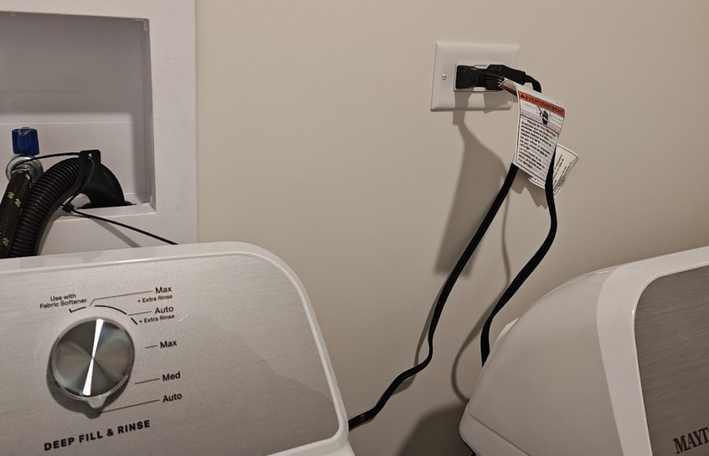 Laundry area showing washing machine plugged into outlet, illustrating GFCI and AFCI code requirements