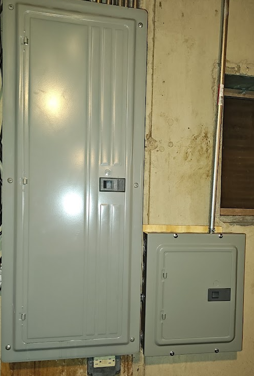 Main service panel and adjacent feeder-supplied subpanel installation showing separate enclosures for NEC 2023 bonding comparison