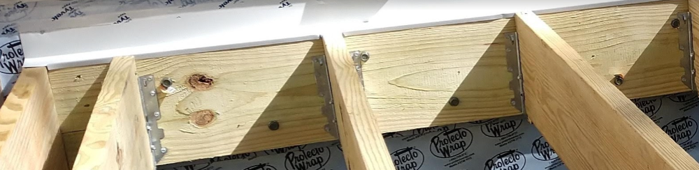 Deck ledger board fastened to house band joist with lag screws showing typical IRC deck ledger attachment