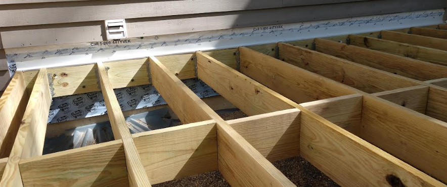 Deck ledger bolt spacing requirements showing lag screws attaching ledger board to house band joist under IRC