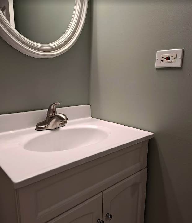 Bathroom GFCI receptacle installed above a vanity illustrating bathroom 20-amp branch circuit requirements.